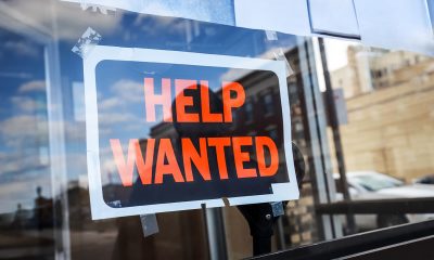 Reflection of a man looking at a help wanted sign in a business